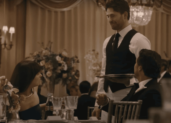 Imagem colorida - Dakota Johnson e Pedro Pascal (sentados) olham para Chris Evans (em pé) em Materialist